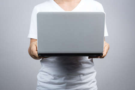 Woman holding laptop on grey backgroundの写真素材