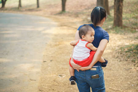 Asian mother giving her 1 year and 4 months son piggyback at the parkの写真素材