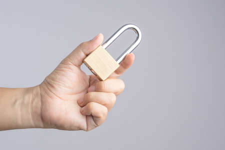 Hand holding metal padlock on white backgroundの写真素材