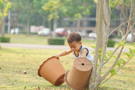 A 1 year and 4 months Asian baby try to planting some tree by using pot as ecology conceptの写真素材