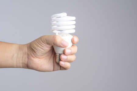 Hand holding compact fluorescent light bulb on white backgroundの写真素材