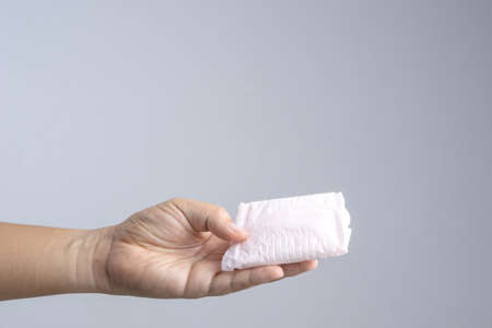 Hand holding sanitary napkin on white backgroundの写真素材