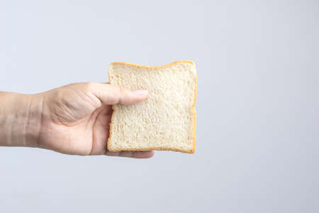 Hand holding sliced whole grain bread on white backgroundの写真素材