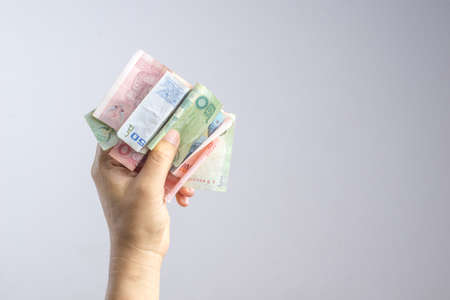 Hand holding Thai money or banknotes on white backgroundの写真素材
