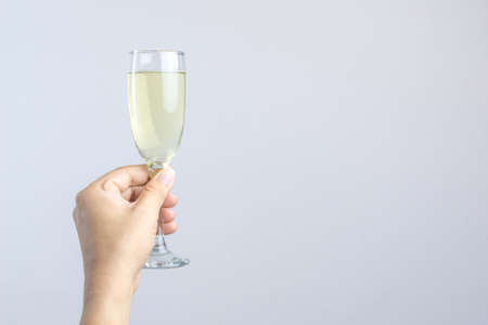 Hand holding glass of champagne for celebration on white backgrounの写真素材