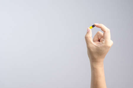 Hand holding medical capsule pill on white backgroundの写真素材