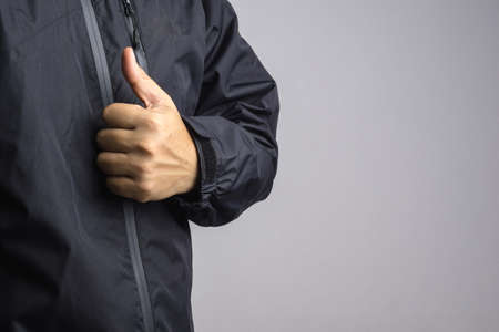 Man wearing black anti static or wet weather jacket or rain coat on white background