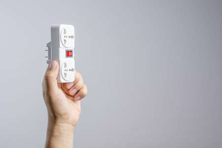 Hand holding universal traveler adapter plug with power switch on white backgroundの写真素材
