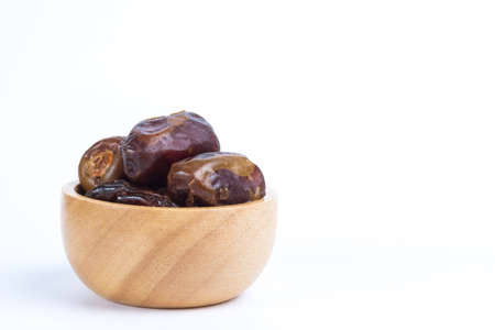 Dried date fruits in small wooden bowl isolated on white backgroundの写真素材