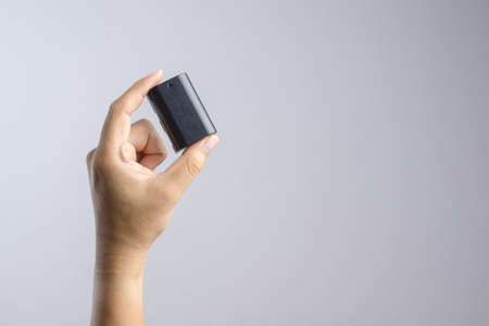 Hand holding camera battery on white backgroundの写真素材