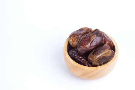 Dried date fruits in small wooden bowl isolated on white backgroundの写真素材