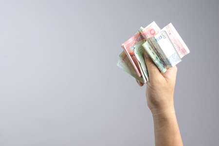 Hand holding Thai money or banknotes on white backgroundの写真素材