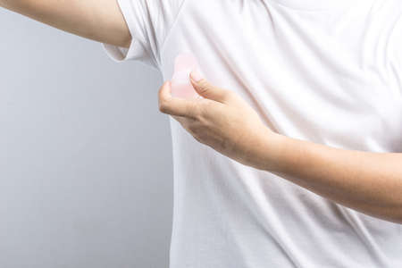 Hand holding natural mineral alum crystal stick use as underarm deodorant on white background