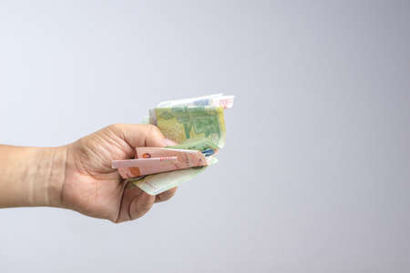 Hand holding Thai money or banknotes on white background