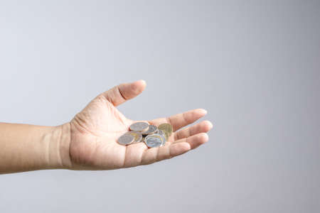 Hand holding Thai coin or currency on white backgroundの写真素材