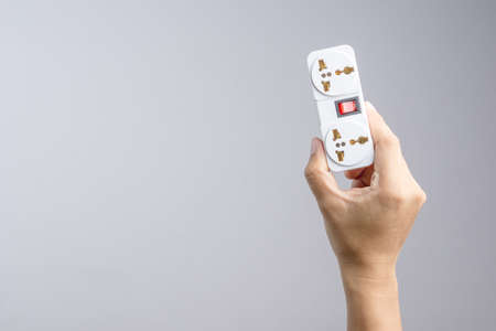 Hand holding universal traveler adapter plug with power switch on white backgroundの写真素材