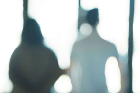 Lens blurred back view of young Asian couple holding hands at the parkの写真素材