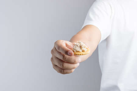 Hand holding instant tuna spread biscuit from convenience store on white backgroundの写真素材