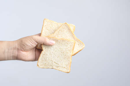 Hand holding sliced whole grain bread on white backgroundの写真素材