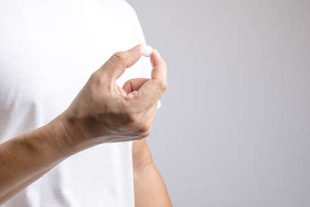 Hand holding medical pill on white backgroundの写真素材
