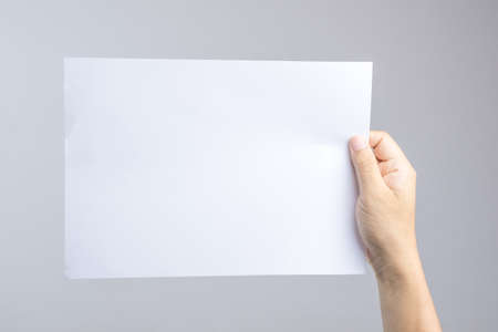 Hand holding blank paper easy replace with poster or brochure on white backgroundの写真素材