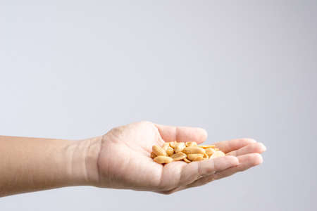 Hand holding heap of salt roasted peanuts on white backgroundの写真素材