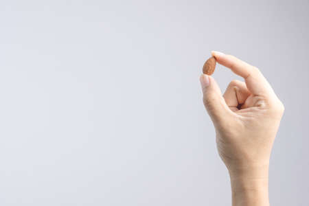 Hand holding heap of organic almonds on white backgroundの写真素材