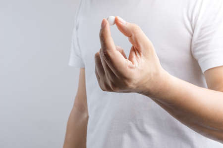 Hand holding medical pill on white backgroundの写真素材