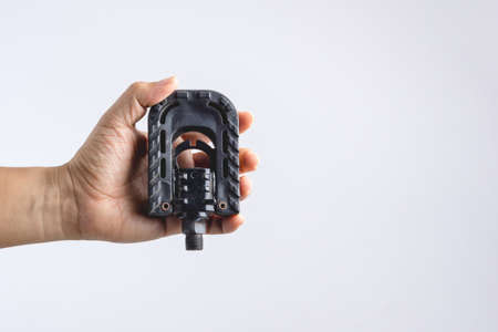 Hand holding used folding bicycle pedal on white backgroundの写真素材