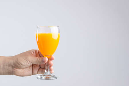 Hand holding glass of orange juice on white backgroundの写真素材
