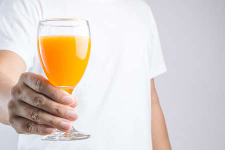 Hand holding glass of orange juice on white backgroundの写真素材