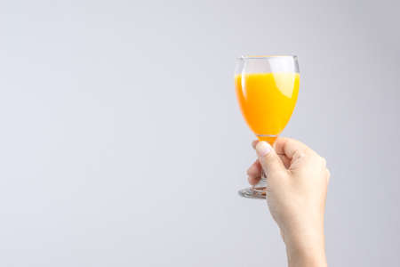 Hand holding glass of orange juice on white backgroundの写真素材