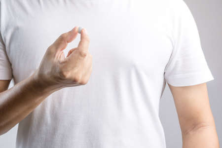 Hand holding medical pill on white backgroundの写真素材