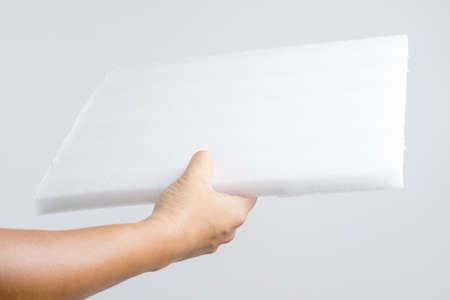 Hand holding foam fiber board on white backgroundの写真素材