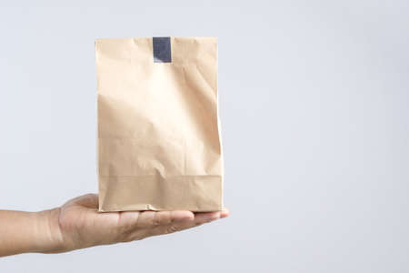 Hand holding brown paper bag on white backgroundの写真素材