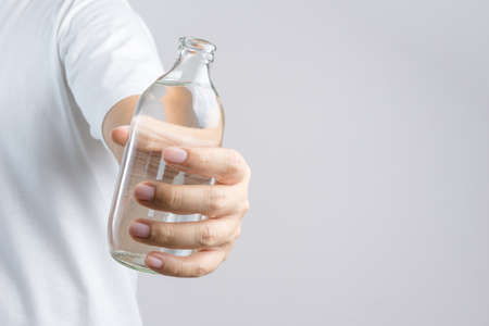 Hand holding glass water bottle on white backgroundの写真素材