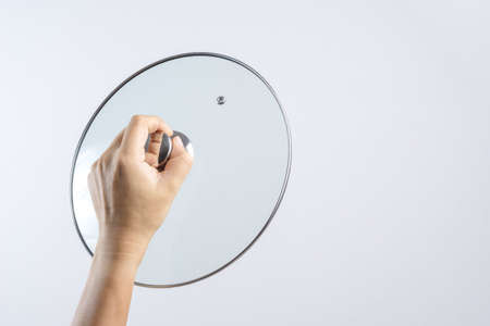 Hand holding glass lid for pan or pot on white backgroundの写真素材