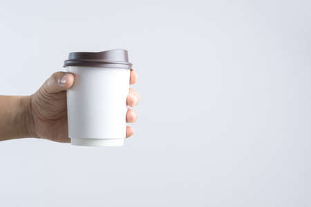Hand holding hot coffee paper cup on white backgroundの写真素材