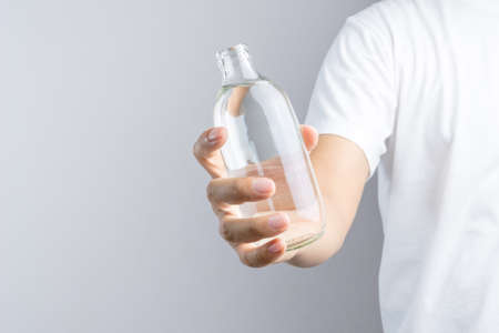 Hand holding glass water bottle on white backgroundの写真素材