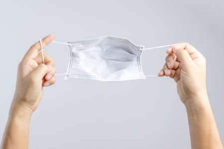 Hand holding black medical protective mask on white backgroundの写真素材