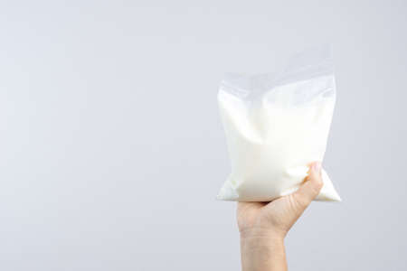 Hand holding a bag of natural yogurt on white backgroundの写真素材