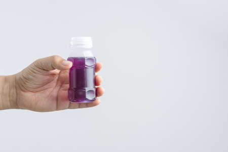 Hand holding a plastic bottle of purple herbal drink from Butterfly pea with lemonade on white backgroundの写真素材