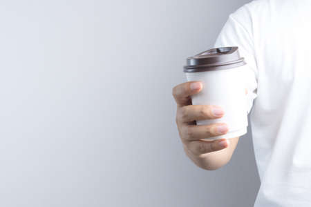 Hand holding hot coffee paper cup on white backgroundの写真素材