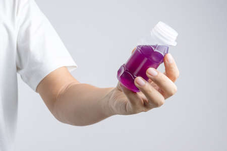 Hand holding a plastic bottle of purple herbal drink from Butterfly pea with lemonade on white backgroundの写真素材