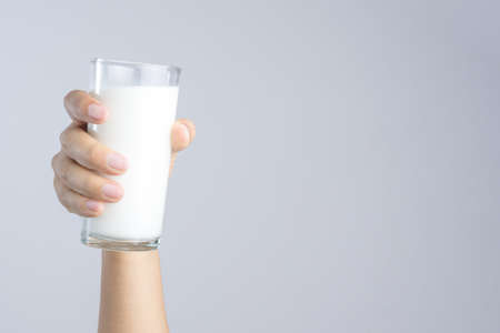 Hand holding a Glass of fresh milk on white backgroundの写真素材