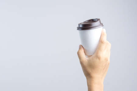 Hand holding hot coffee paper cup on white backgroundの写真素材