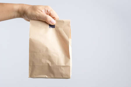 Hand holding brown paper bag on white backgroundの写真素材