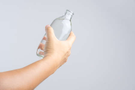 Hand holding glass water bottle on white backgroundの写真素材