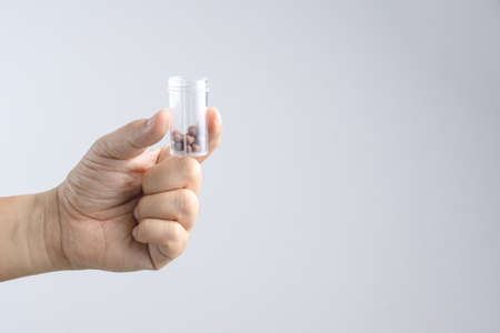 Hand holding traditional Asian herbal medicine pills on white backgroundの写真素材