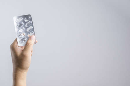 Hand holding empty medical pill on white backgroundの写真素材